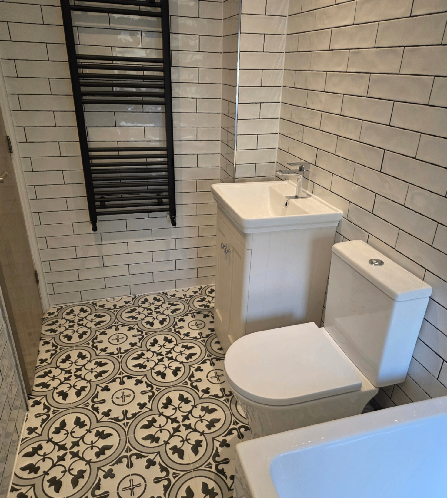 Metro tile bathroom with patterned floor and black heated towel rail — real Blue Sky client home