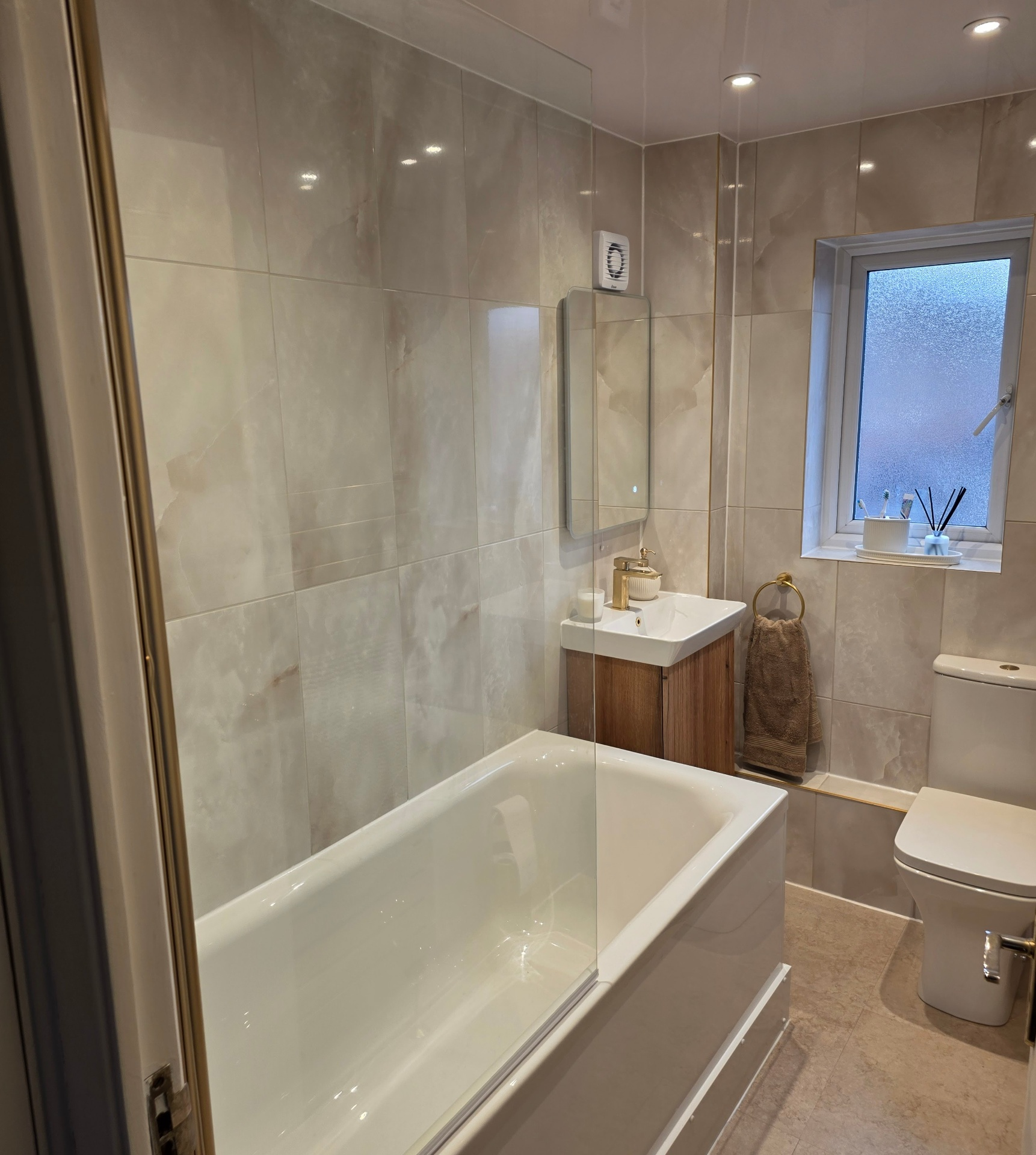 Beige marble-effect family bathroom with brass fixtures — real Blue Sky client home
