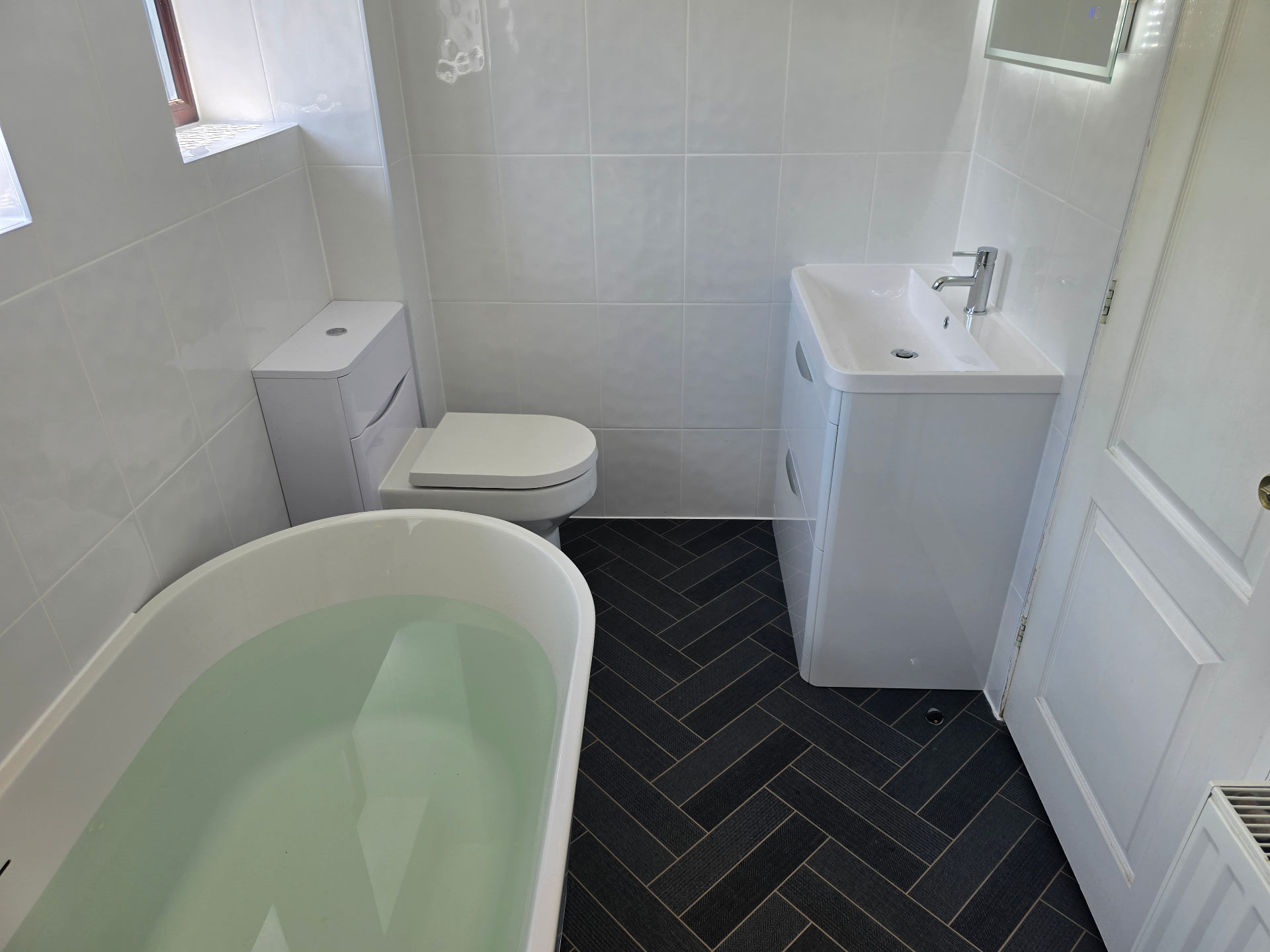 WC and vanity with dark herringbone floor tiling in a refurbished Tamworth bathroom