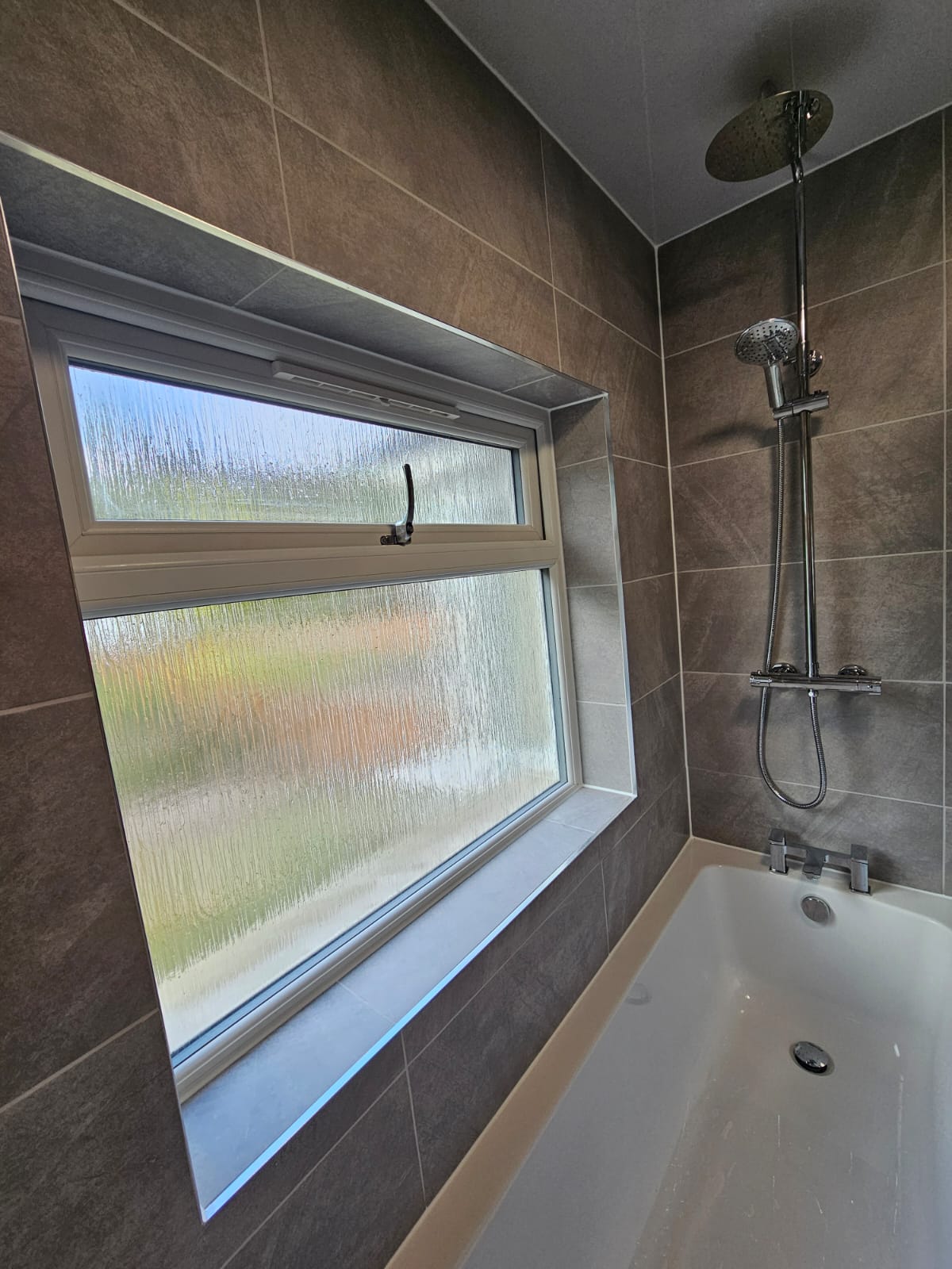 Bath and shower installation with grey wall tiling in a Tamworth bathroom