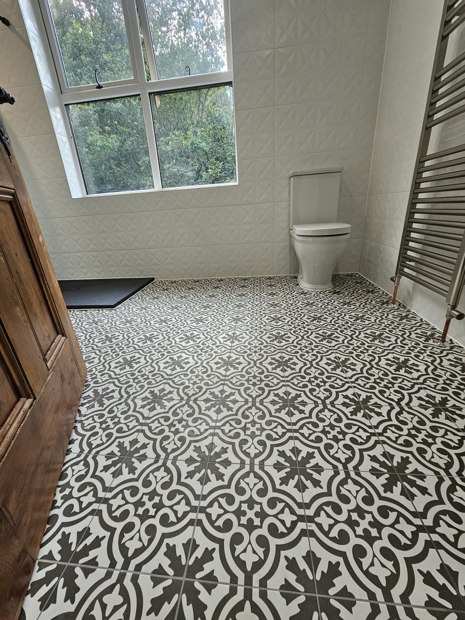 Patterned encaustic-style floor tiling with textured white wall tiles in a Tamworth bathroom