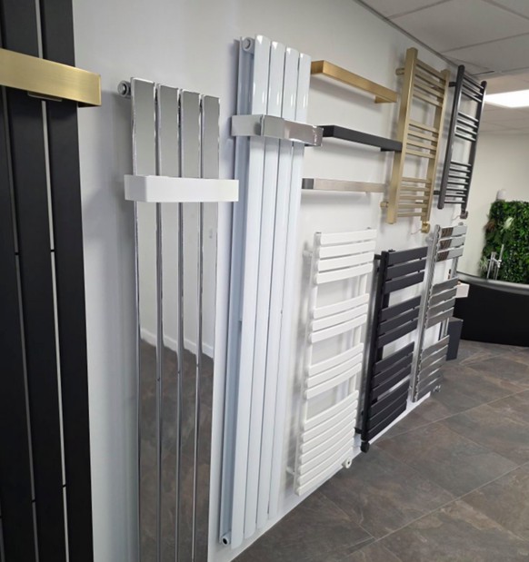 Wall-mounted display of designer heated towel rails in chrome, gold and matt black at the Tamworth showroom