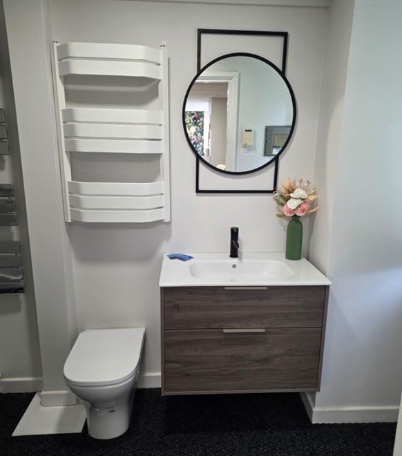 Wood-effect floating vanity with white sculpted towel rail and round mirror at the Tamworth bathroom showroom