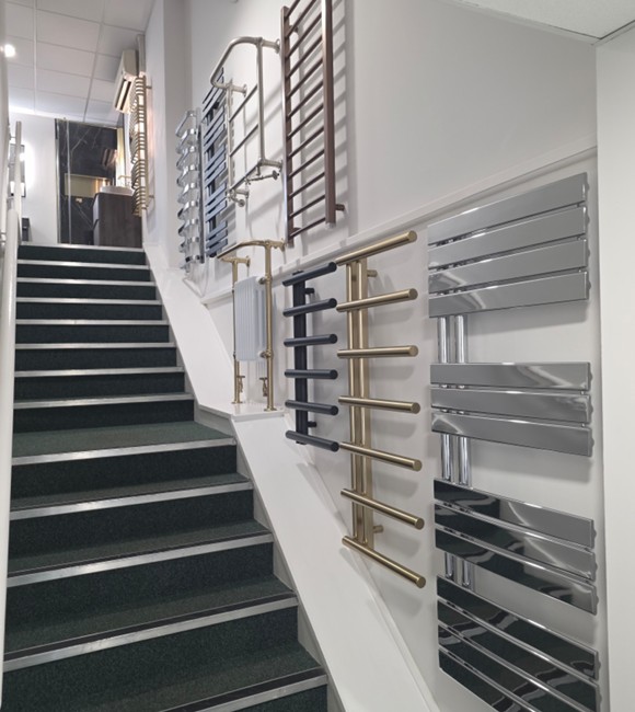 Stairwell wall display of designer heated towel rails leading to the upstairs showroom in Tamworth