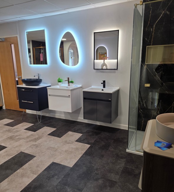 Three wall-hung vanity units with backlit mirrors above stone-effect flooring at the Tamworth bathroom showroom