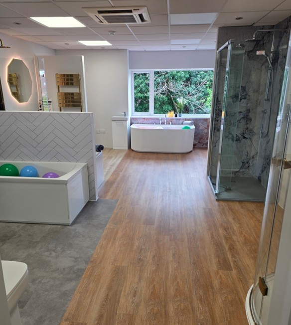 Freestanding bath beside a marble-effect walk-in shower with bright window lighting at the Blue Sky Tamworth bathroom showroom